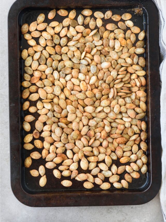 Roasted pumpkin seeds covering an entire baking sheet.