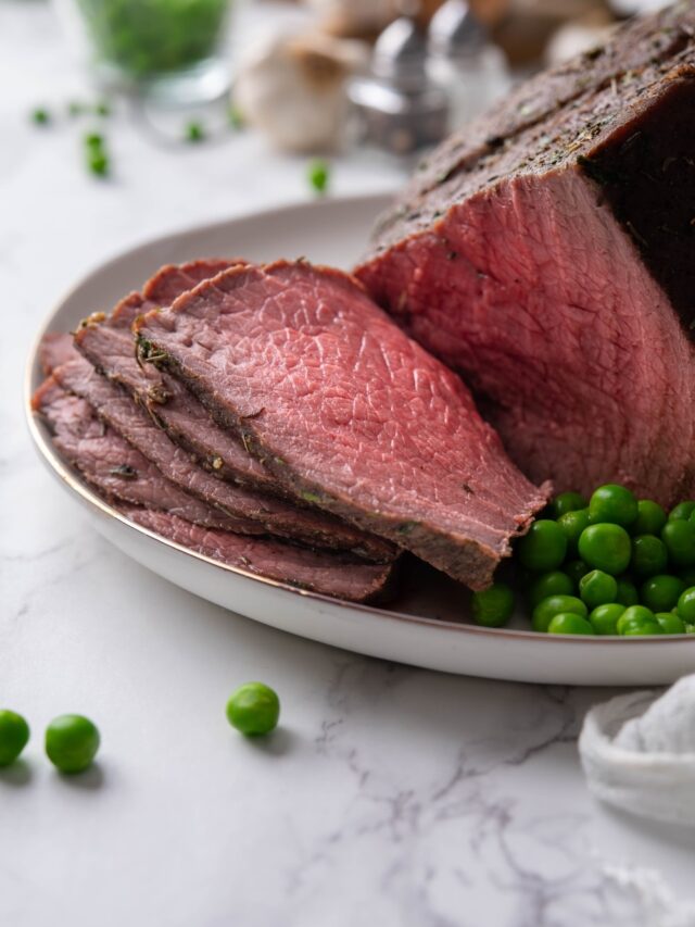 Medium rare sirloin tip roast slices on a plate.