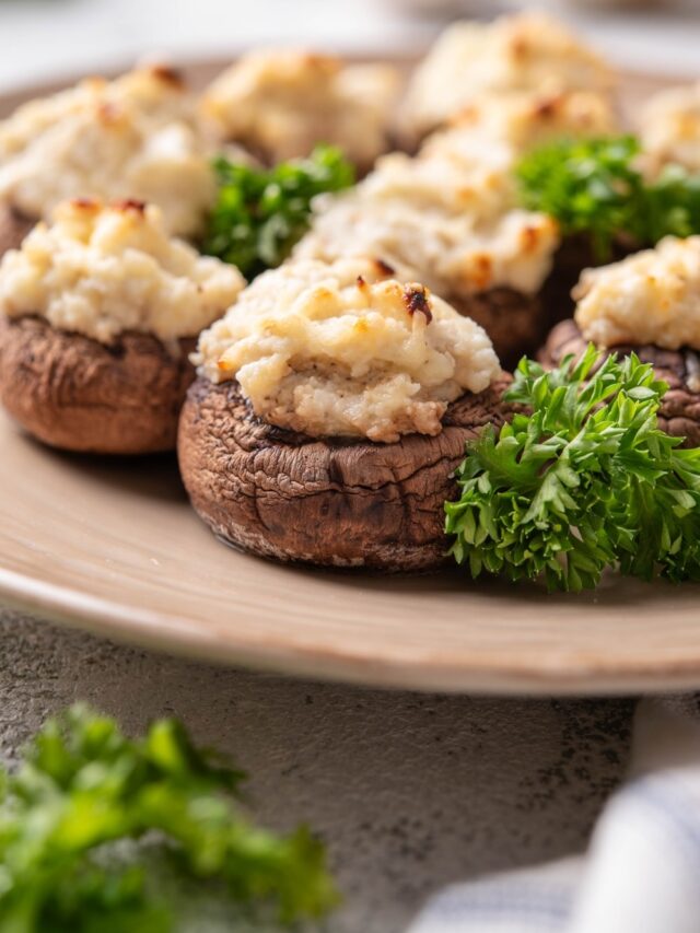 A cream cheese stuffed mushroom on part of a plate with more mushrooms behind it.
