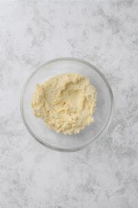 A glass bowl full of biscuit dough on a white counter.