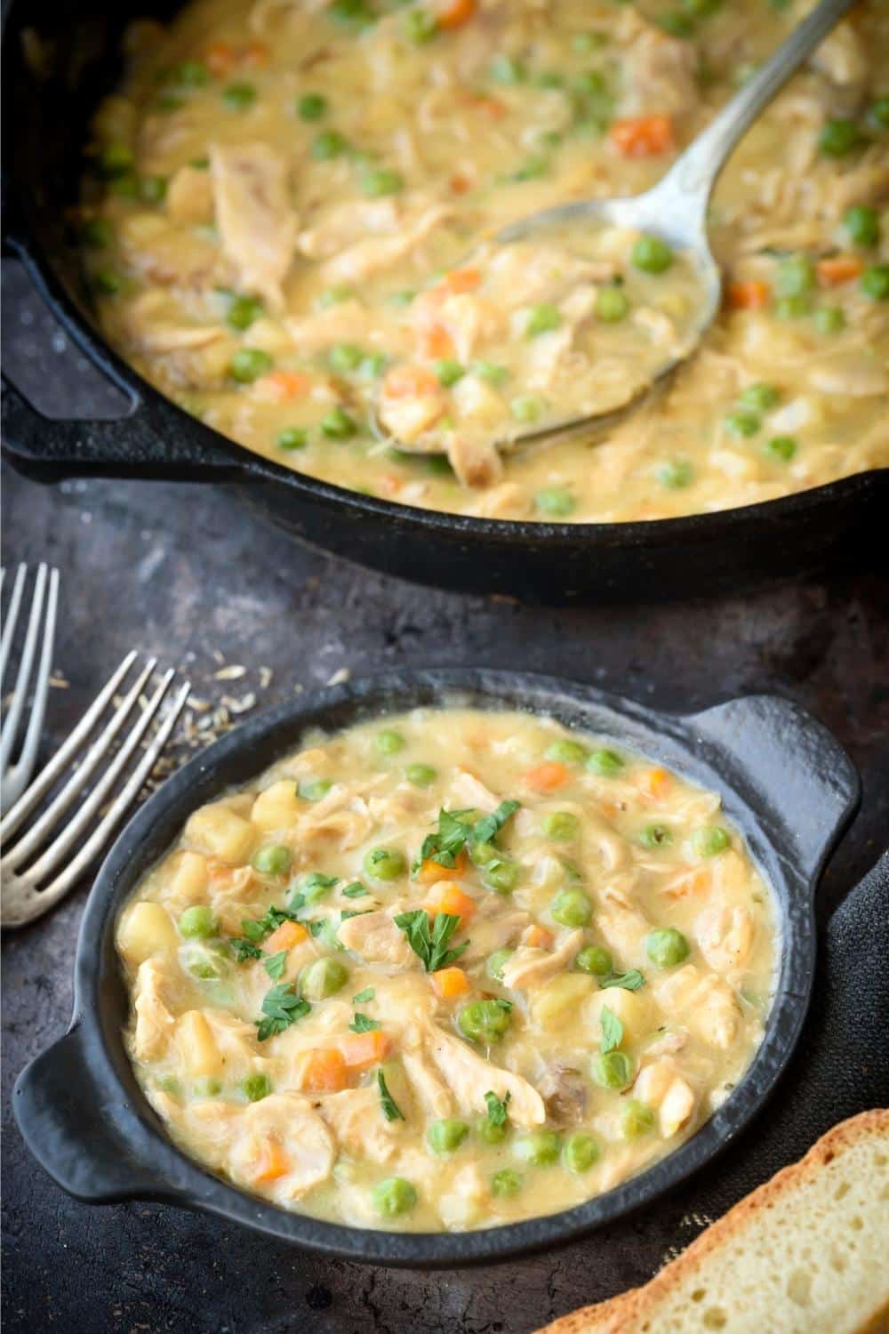 A large pot of crustless chicken pot pie and a spoon, next to a smaller serving pot of crustless chicken pot pie.