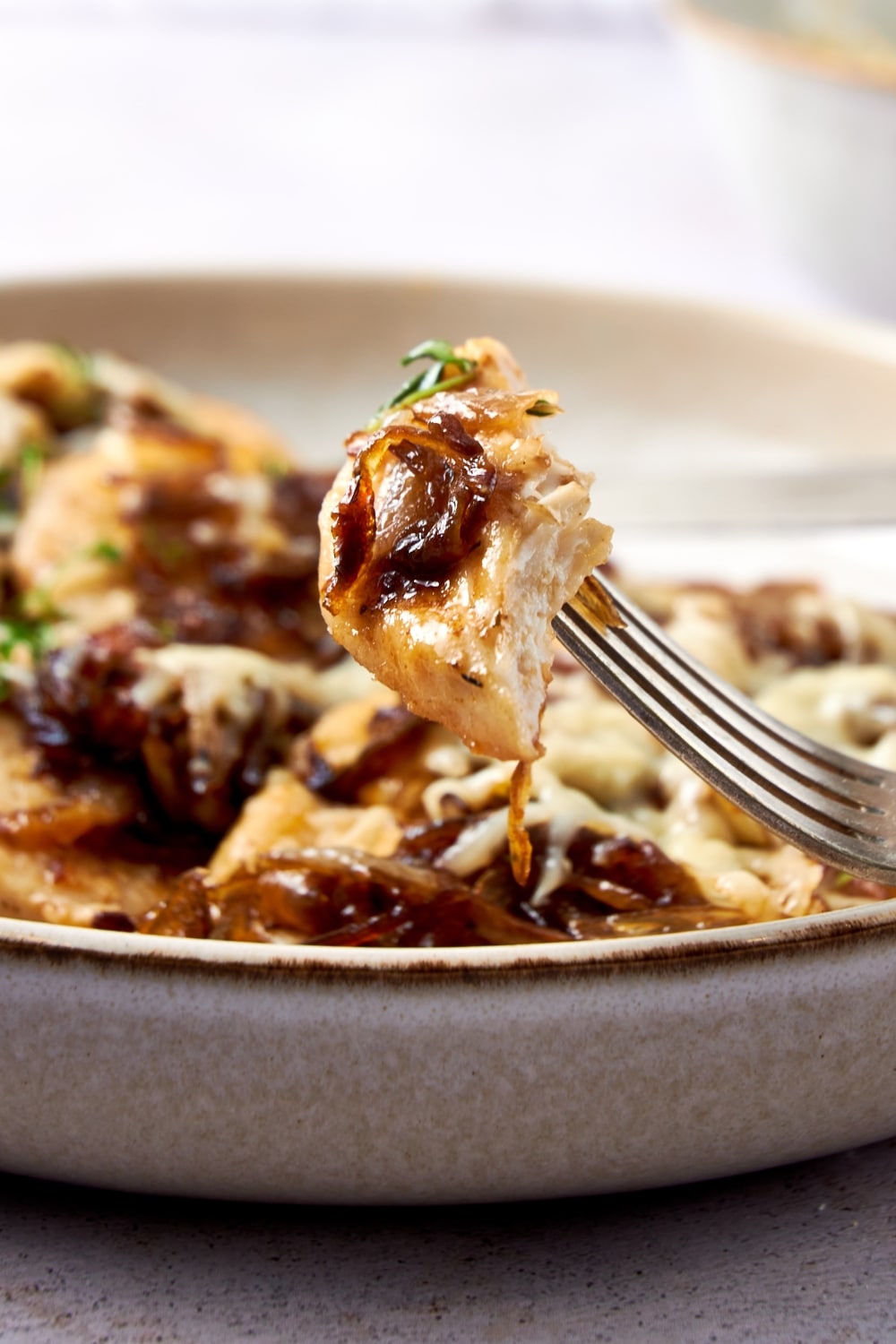 A closer look at a bite of French onion chicken on a fork.