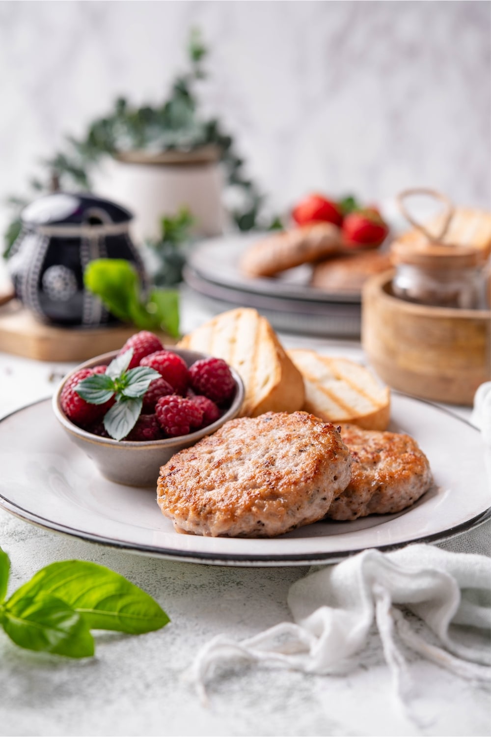 A turkey sausage breakfast plate with toasted baguette slices and raspberries.