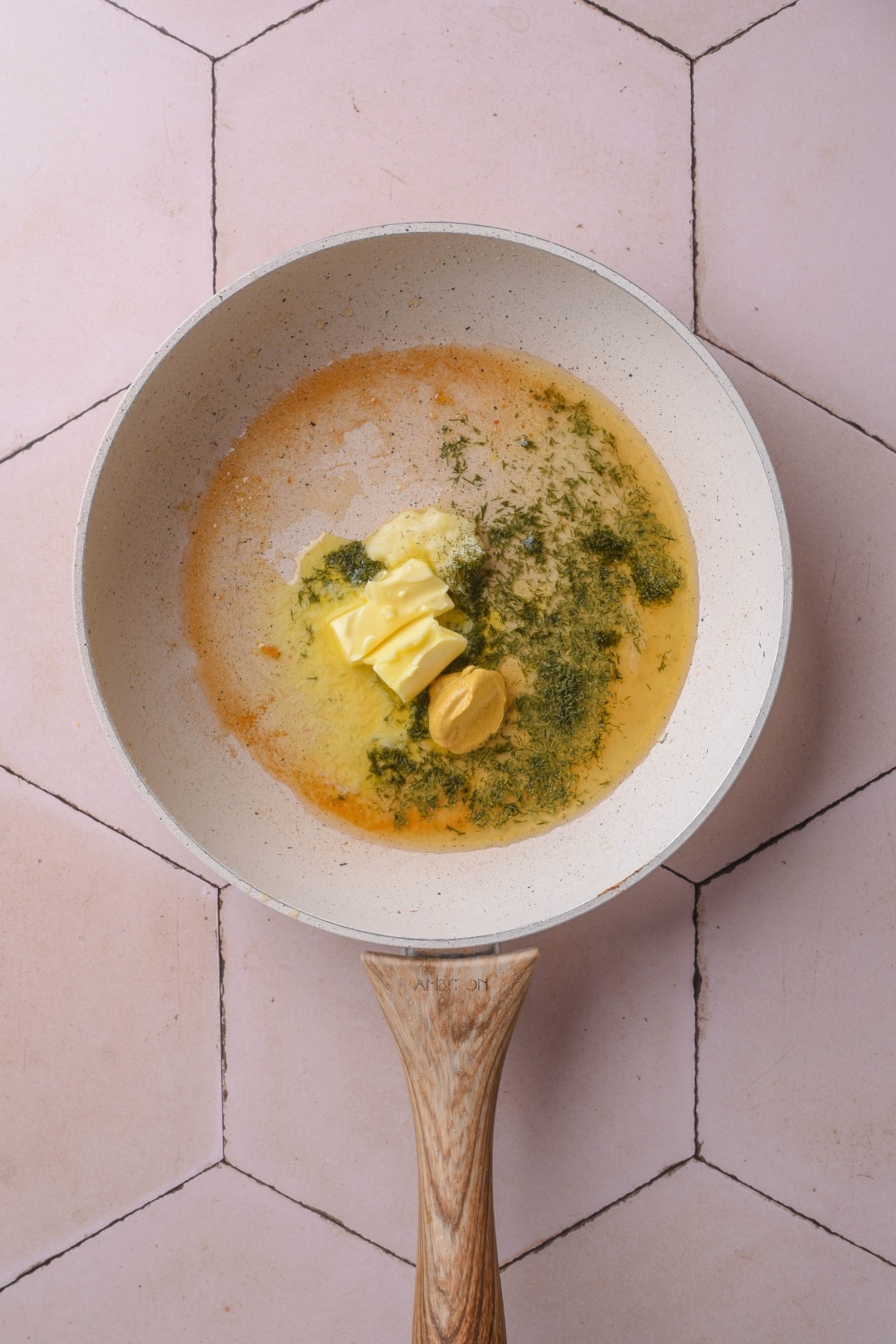 Butter, mustard, and dried dill in a pan.