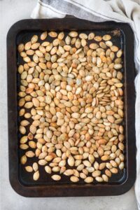 Roasted pumpkin seeds covering an entire baking sheet.