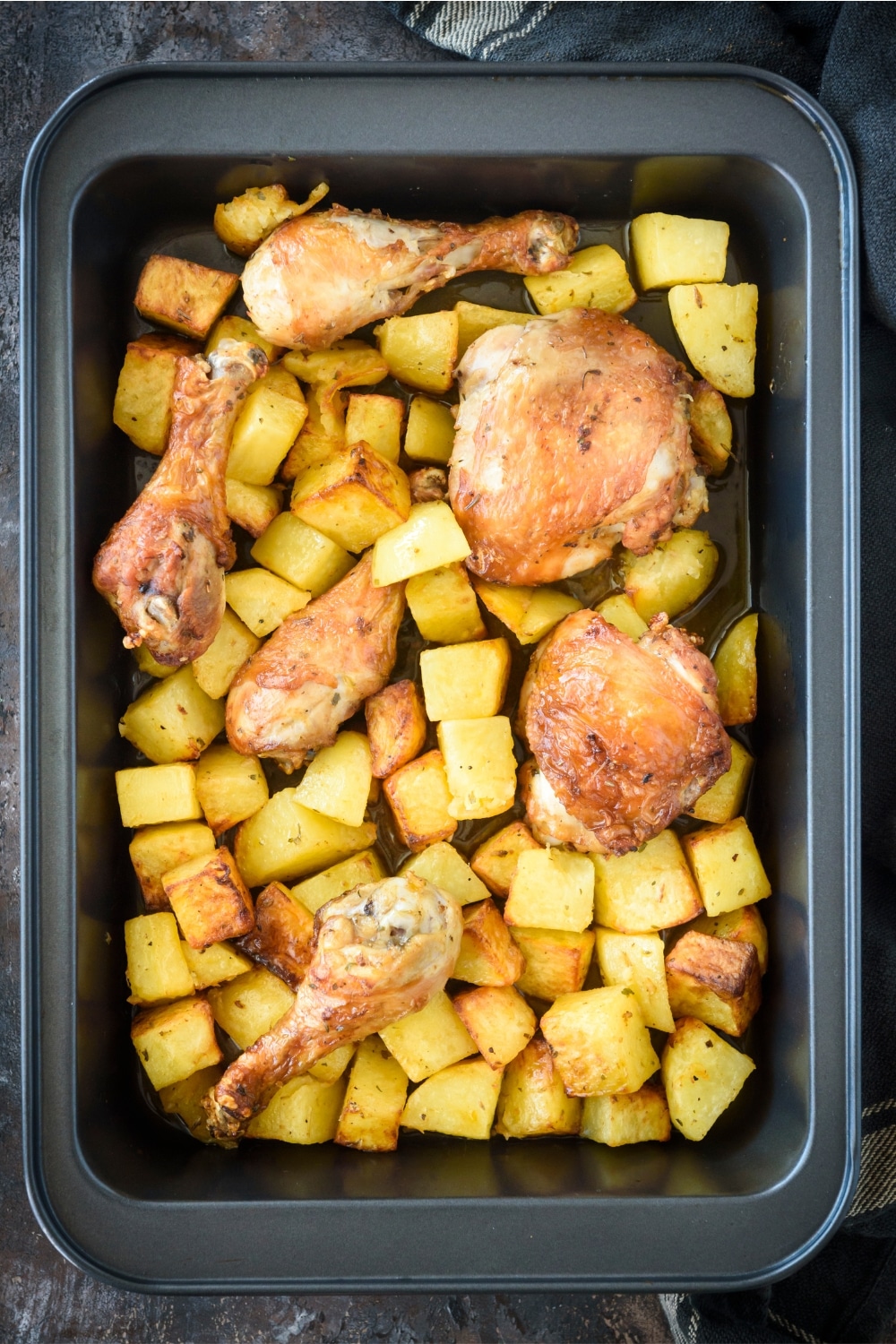 Chicken and potatoes in a black baking dish.