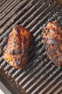 Two flank steaks cooked on top of a grill.