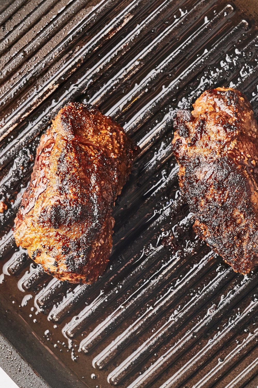 Two flank steaks cooked on top of a grill.