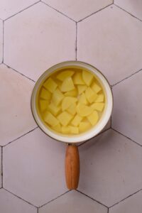 A bunch of diced potatoes in water in a pot on a white counter.