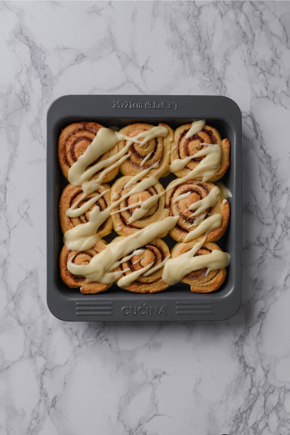 Protein cinnamon rolls in a baking dish topped with icing.