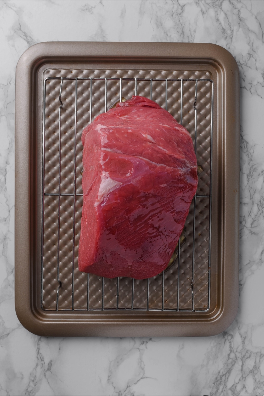 Raw sirloin tip on a roasting pan.