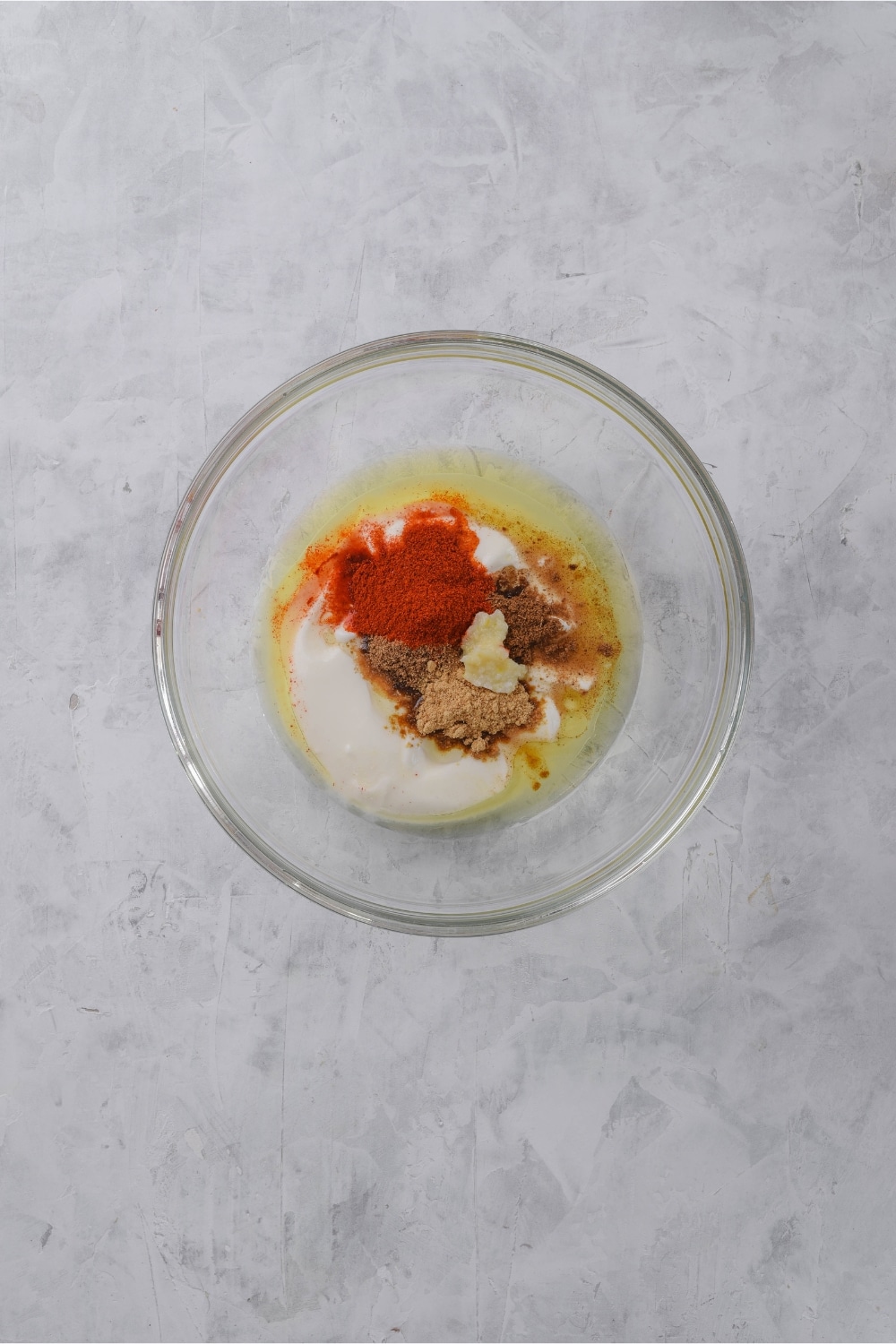 Unmixed yogurt marinade ingredients in a glass bowl.