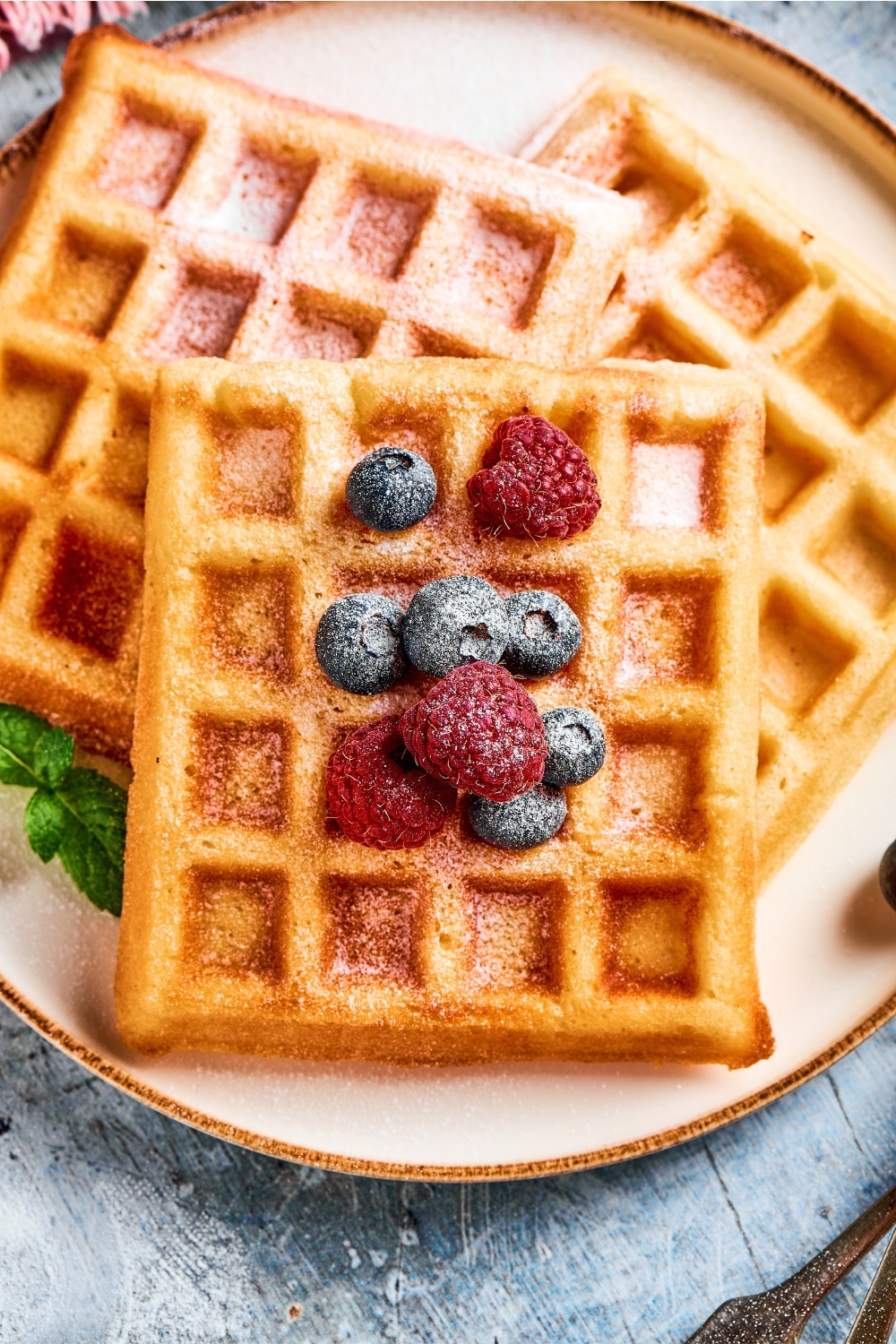 Three waffles overlapping one another on a white plate.