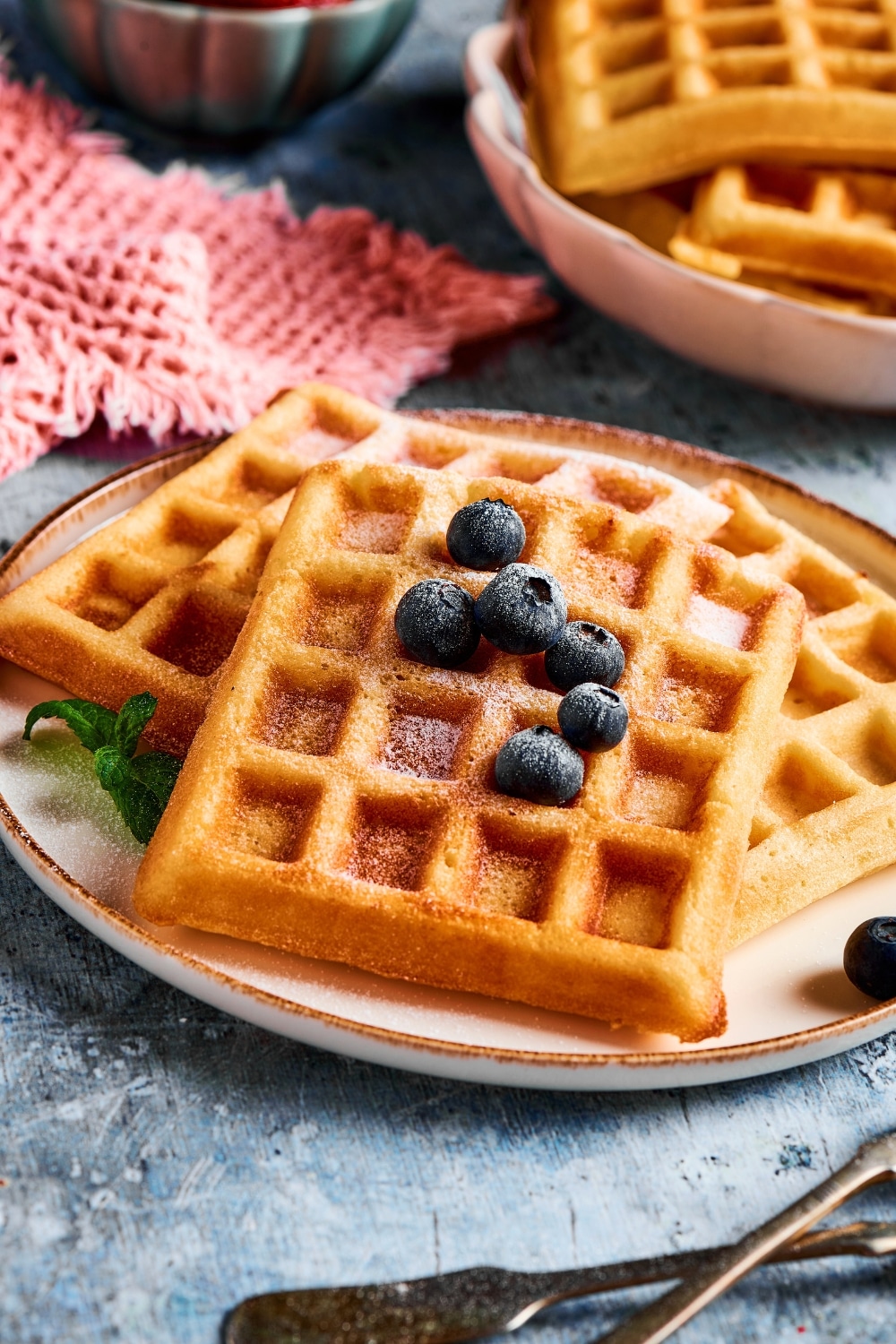 Three waffles on top of one another on a plate.