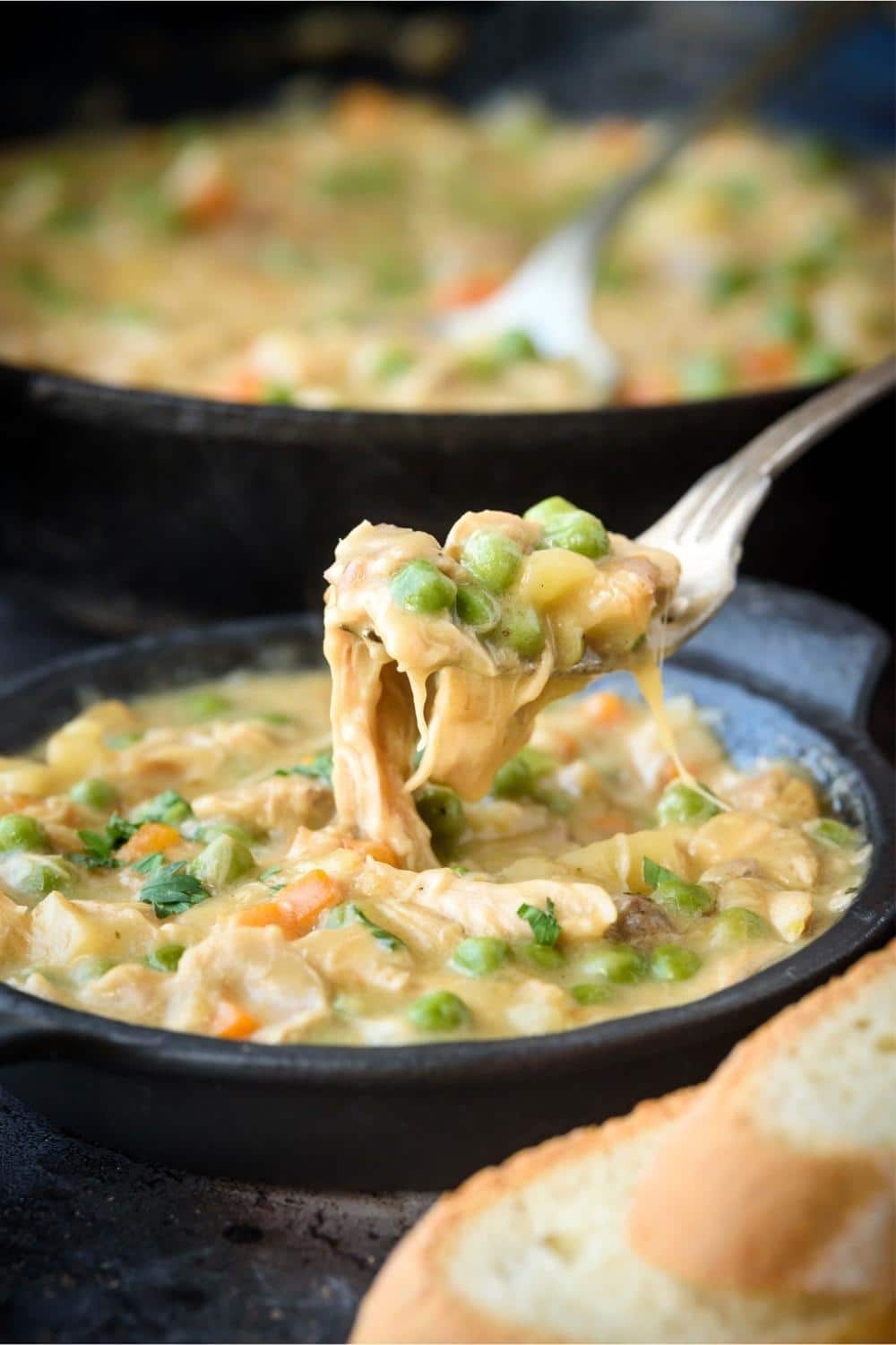 Lifting a forkful of crustless chicken pot pie from a small cast iron serving bowl.