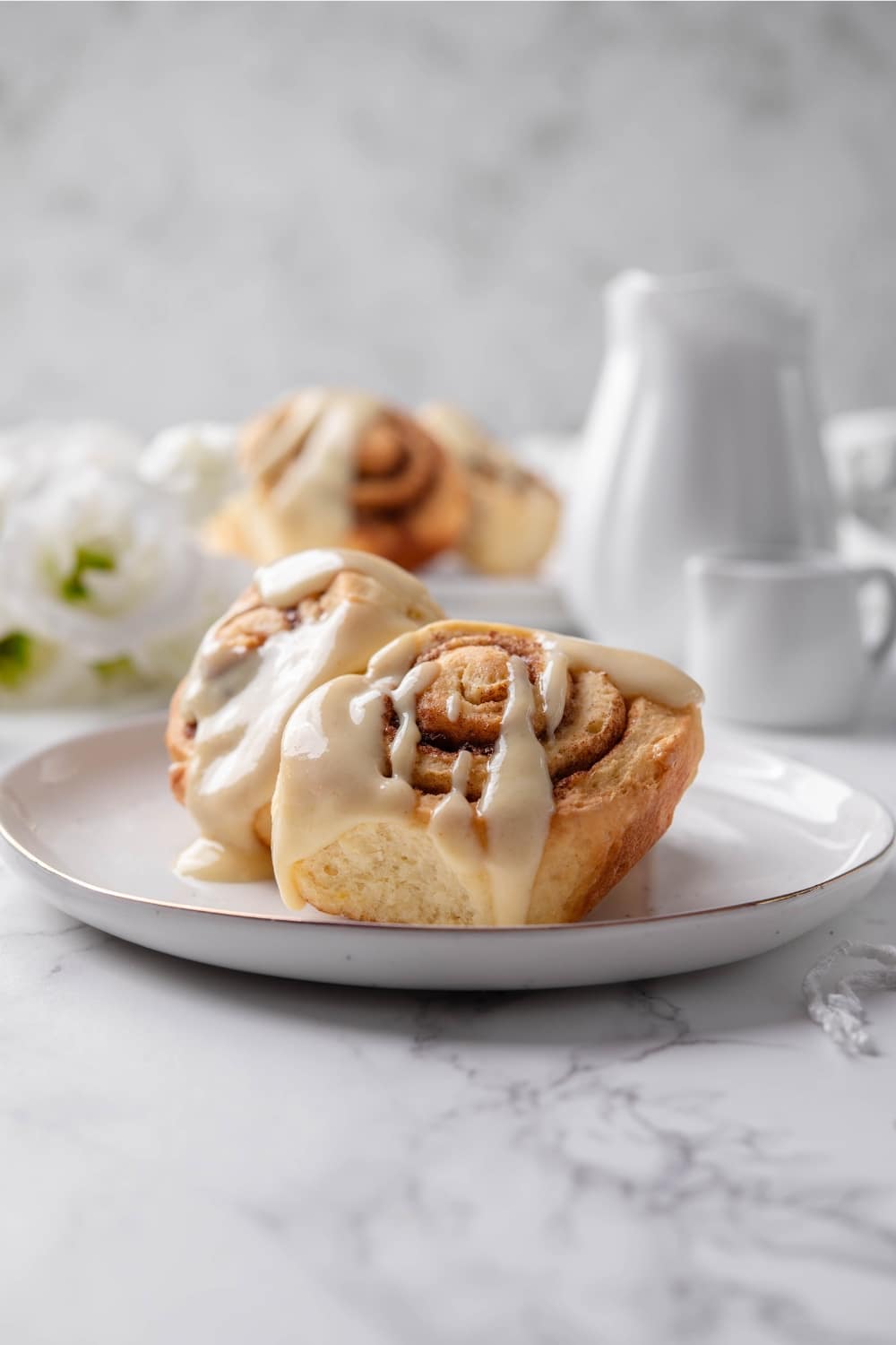 A plate of protein cinnamon rolls topped with icing.