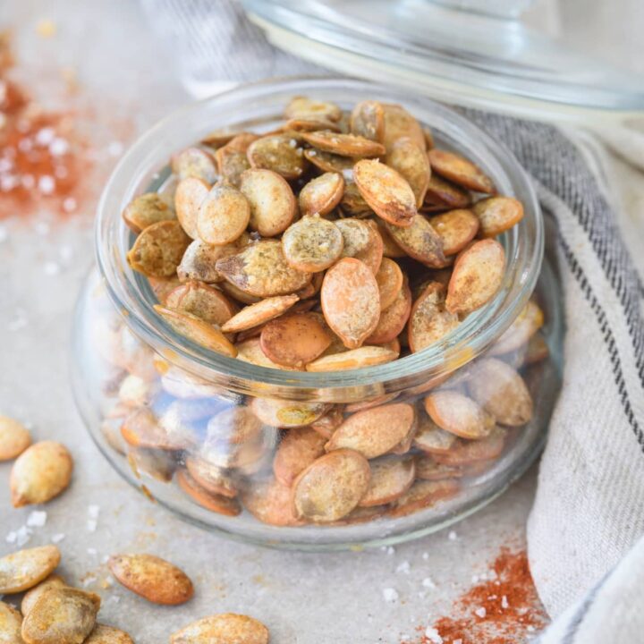 A glass jar that is filled with pumpkin seeds.