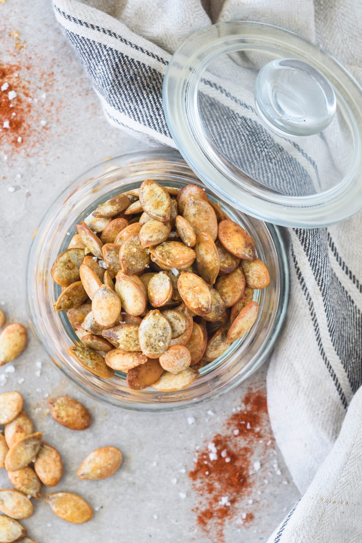 Pumpkin seeds in a glass jar on top of a white counter.