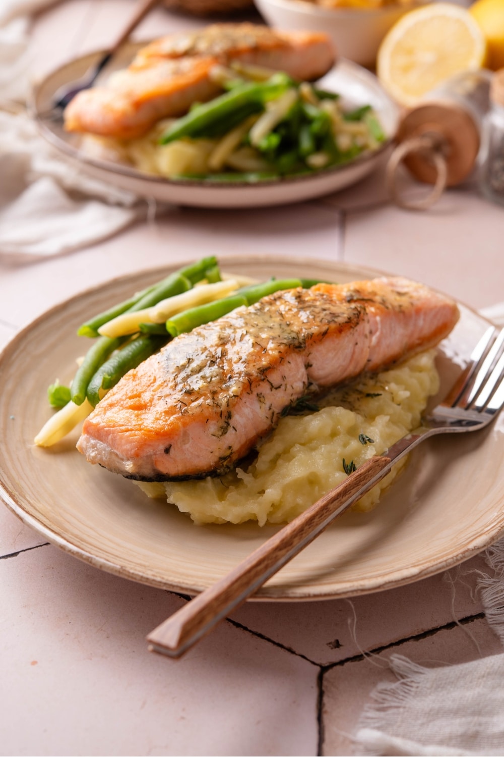 Salmon on top of mashed potatoes on a plate.