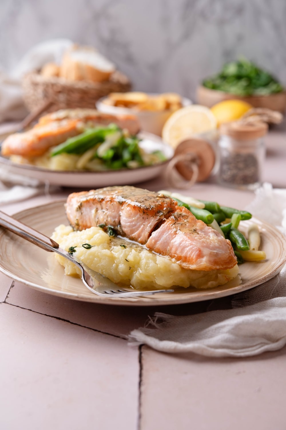 A piece of salmon on top of mashed potatoes on a white plate.