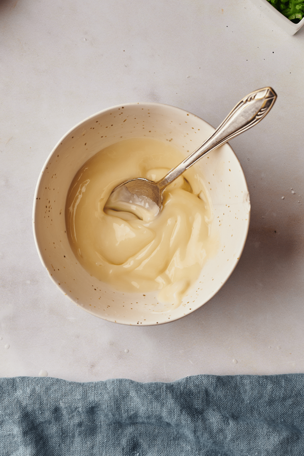 A bowl of creamy sauce with a spoon in it.