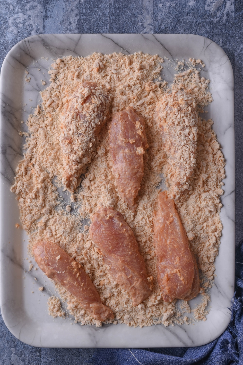 Seasoning on top of chicken tenders on a grey plate.