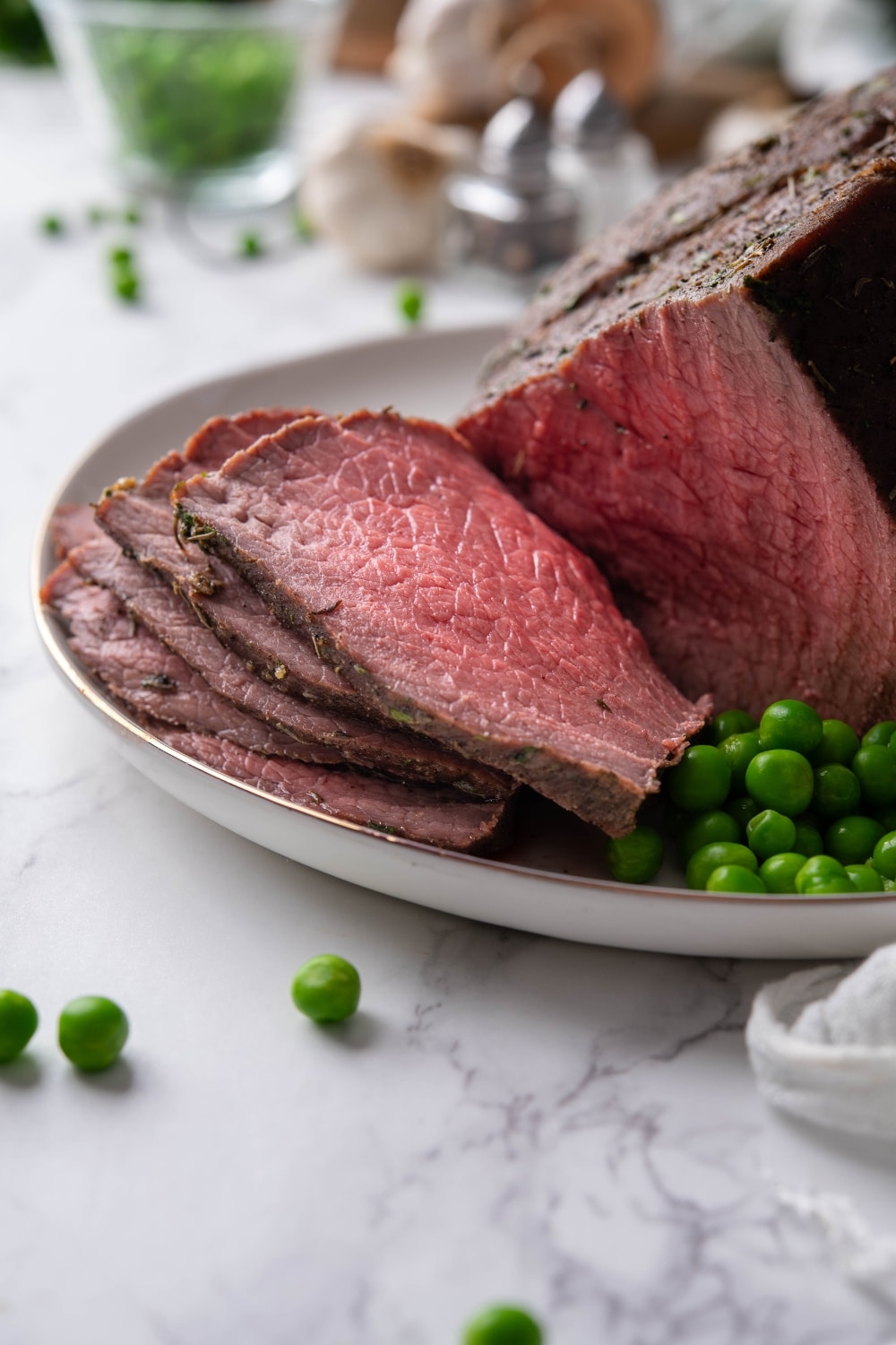 Medium rare sirloin tip roast slices on a plate.