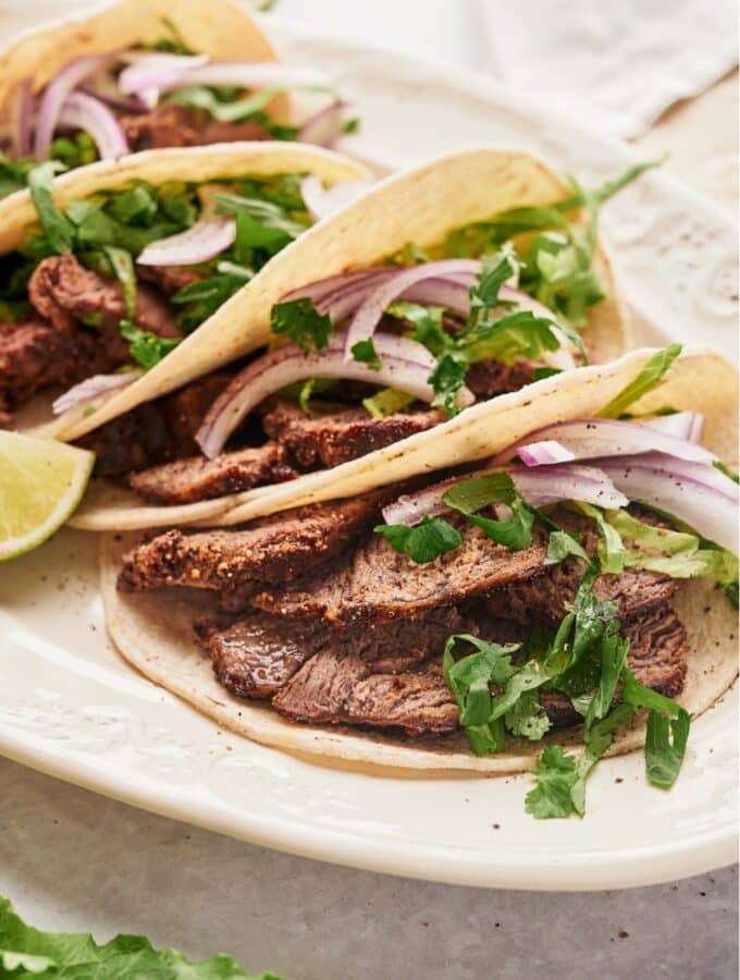 Steak, red onion, and cilantro in a flour tortilla. Behind it are a few more steak tacos.