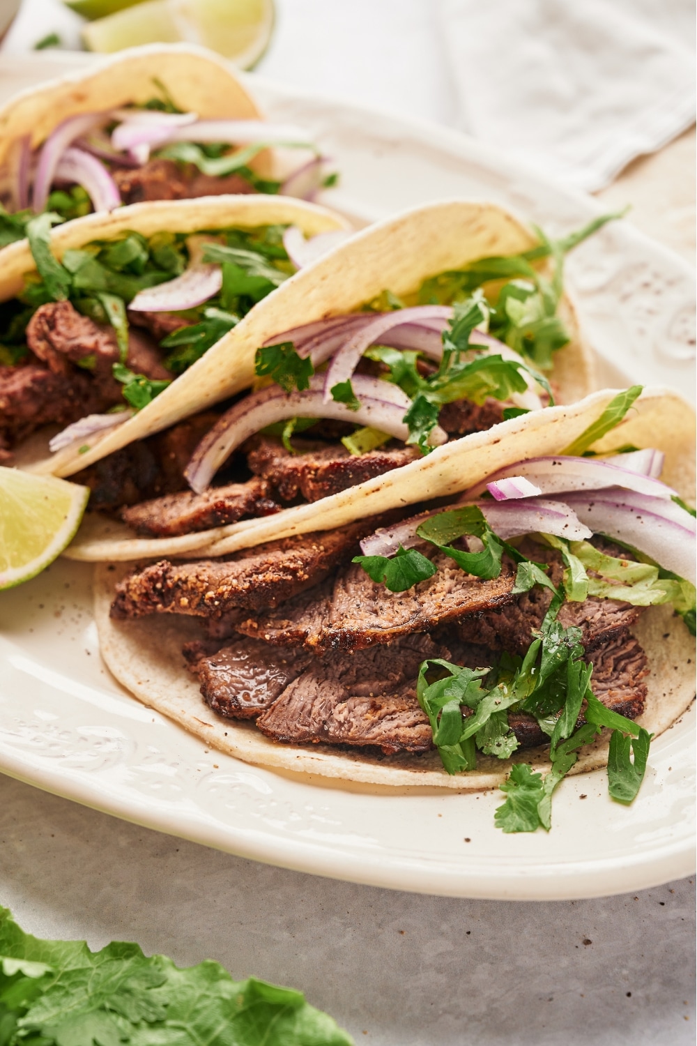 Steak, red onion, and cilantro in a flour tortilla. Behind it are a few more steak tacos.