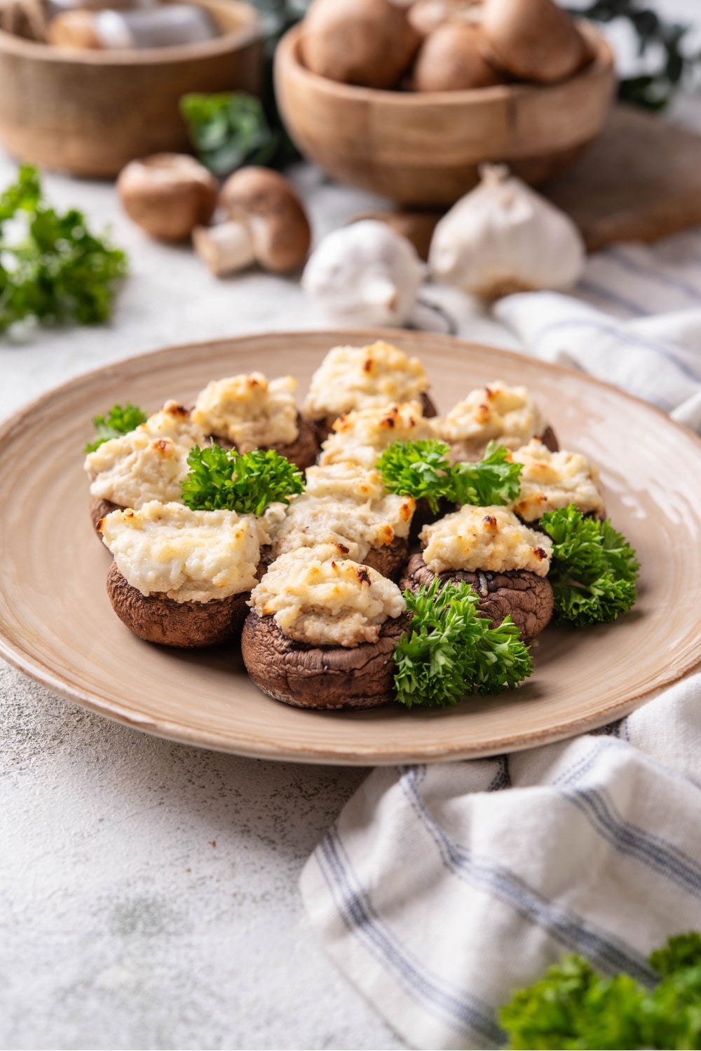 A couple of cream cheese stuffed mushrooms on a plate that is on a grey counter.