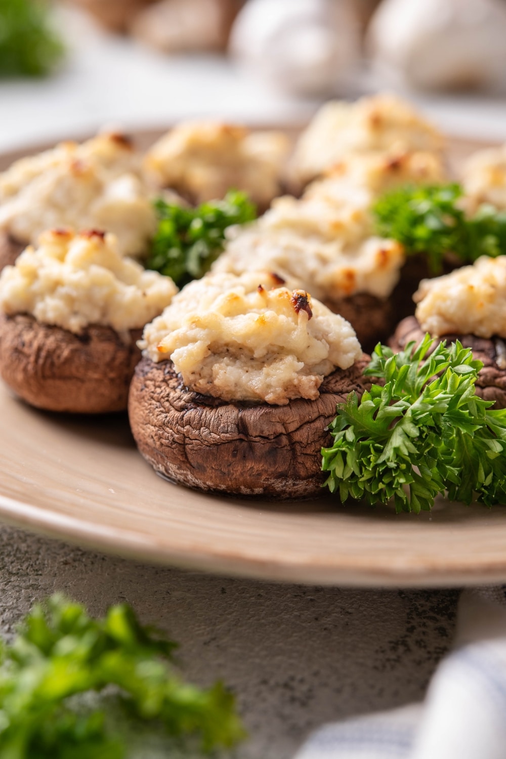 A cream cheese stuffed mushroom on part of a plate with more mushrooms behind it.