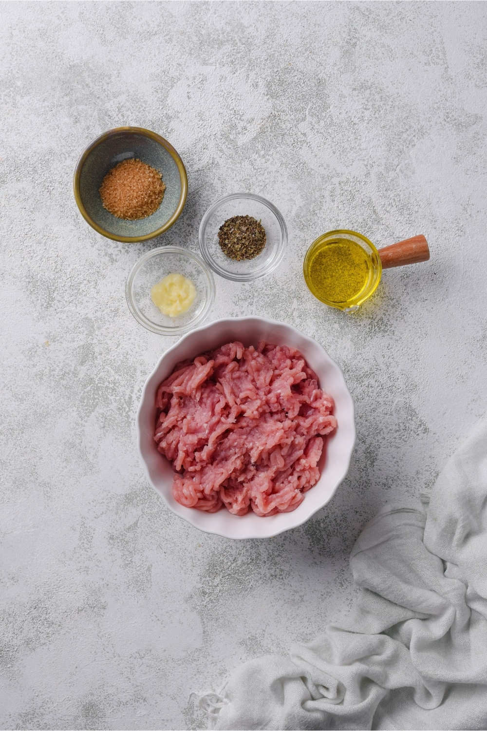 Bowls of ground turkey, minced garlic, brown sugar, dried thyme, and olive oil.