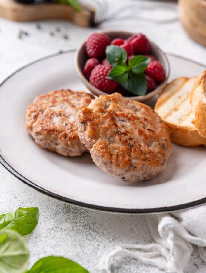 Two turkey breakfast sausages served with toasted baguette slices and berries.