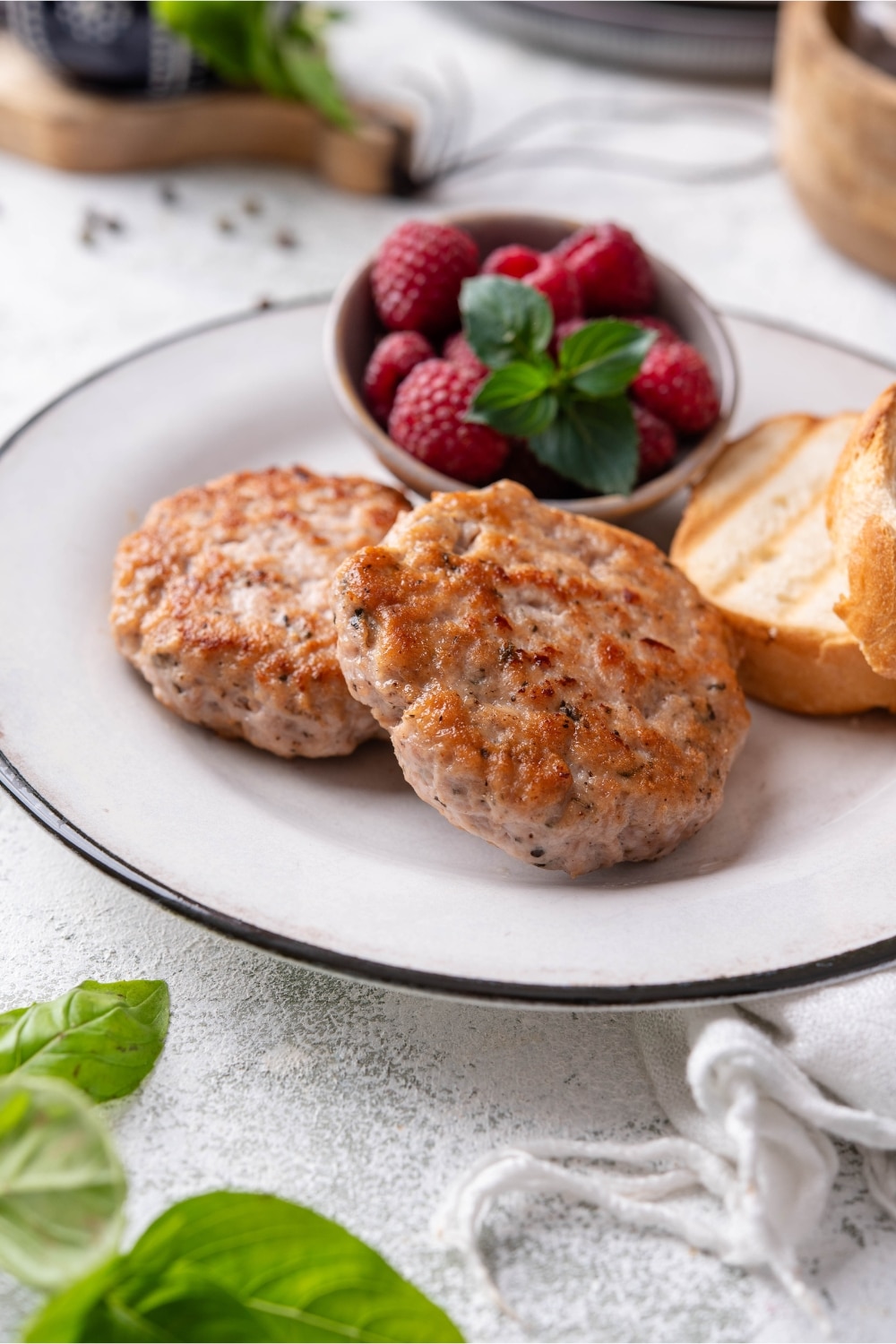 Two turkey breakfast sausages served with toasted baguette slices and berries.