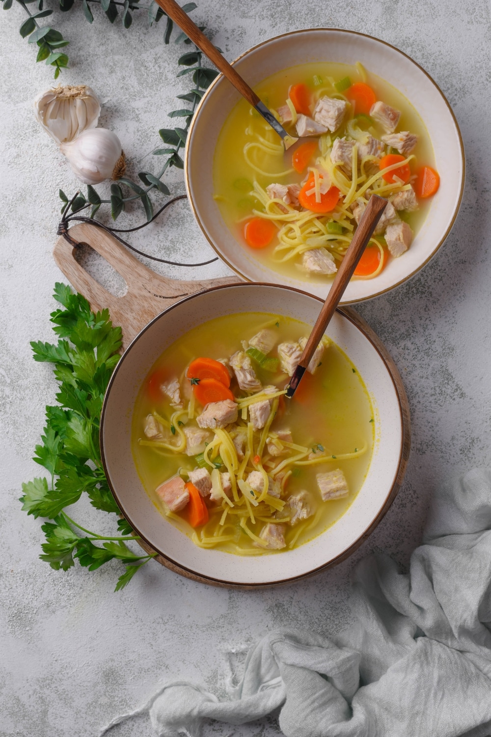 Overhead view of two bowls of turkey noodle soup with chunks of carrots and celery. There is a spoon in each bowl.