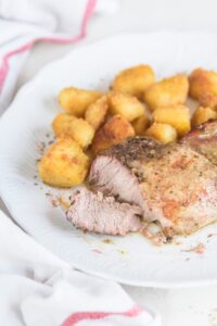 A pork chop cut into smaller pieces on a plate with a side of tater tots.