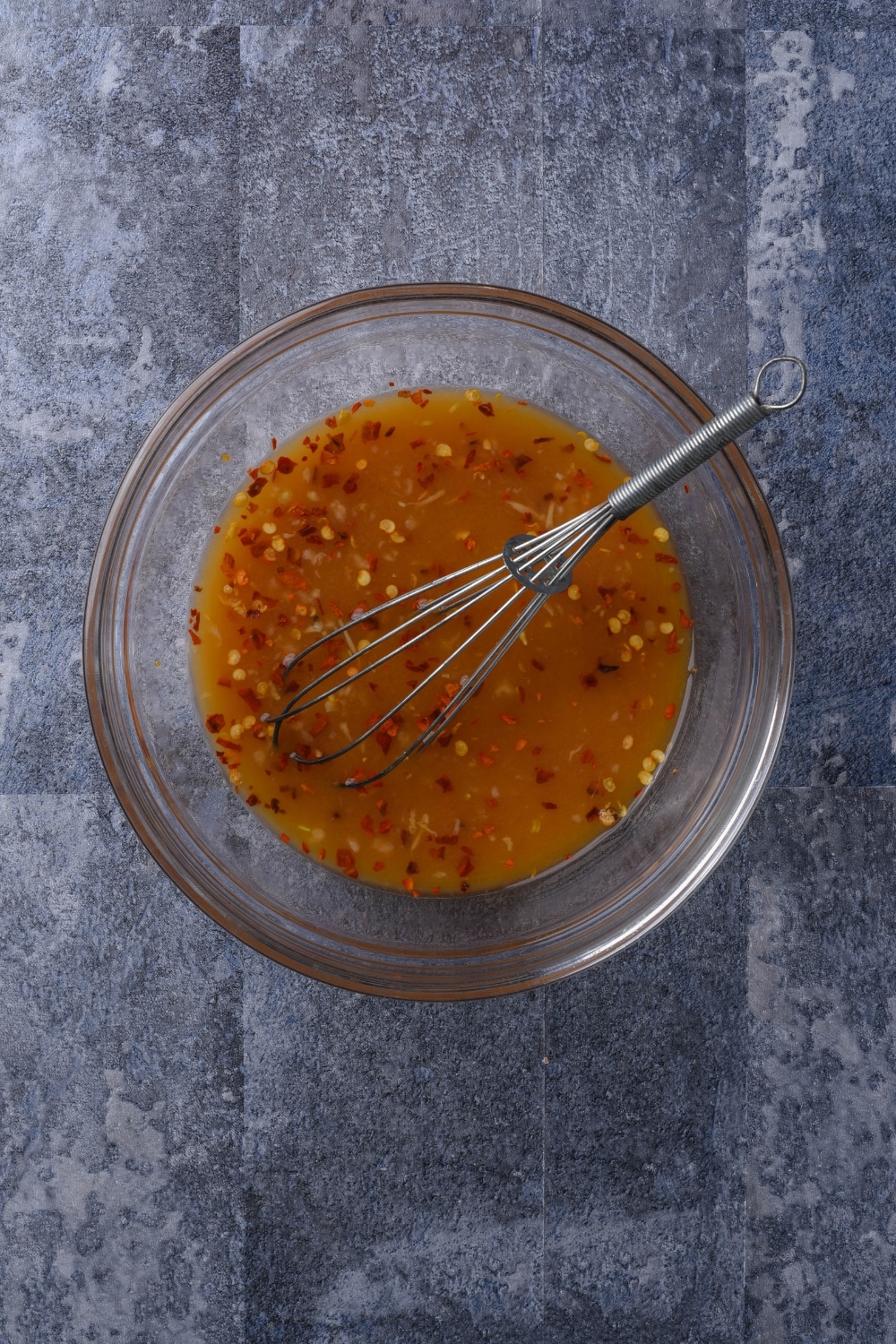 A bowl of orange sauce with a whisk in the bowl.