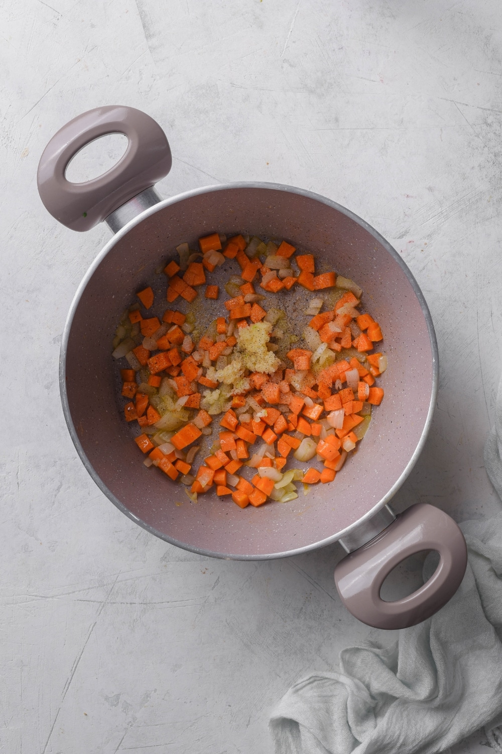 A pot filled with diced carrots, onion, and minced garlic.