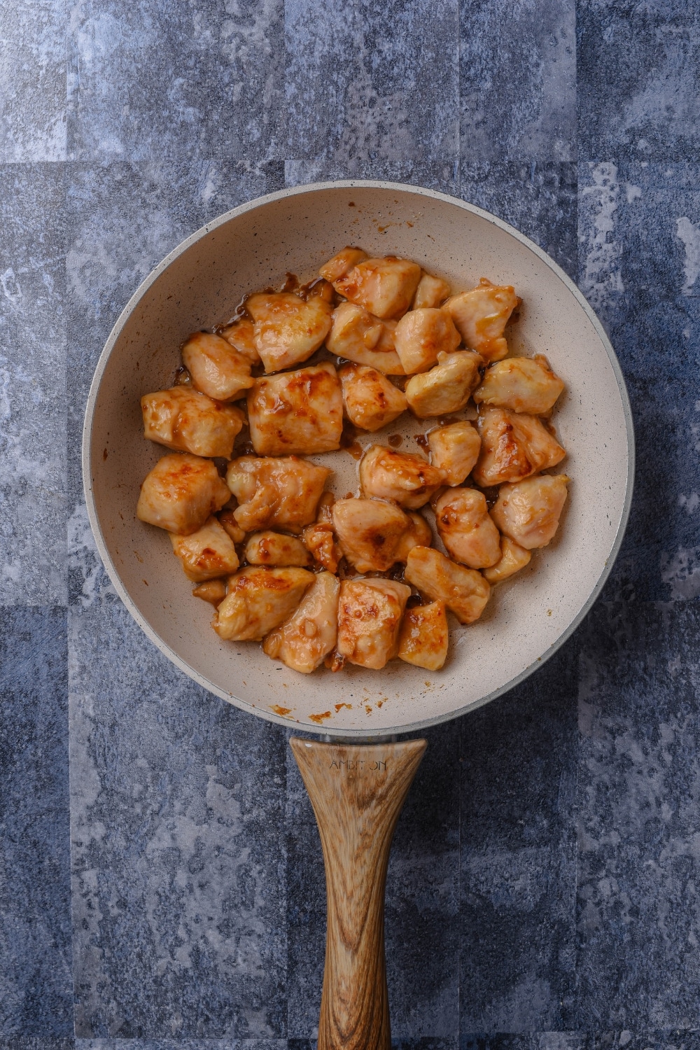 A skillet with seasoned chicken cooking in it.