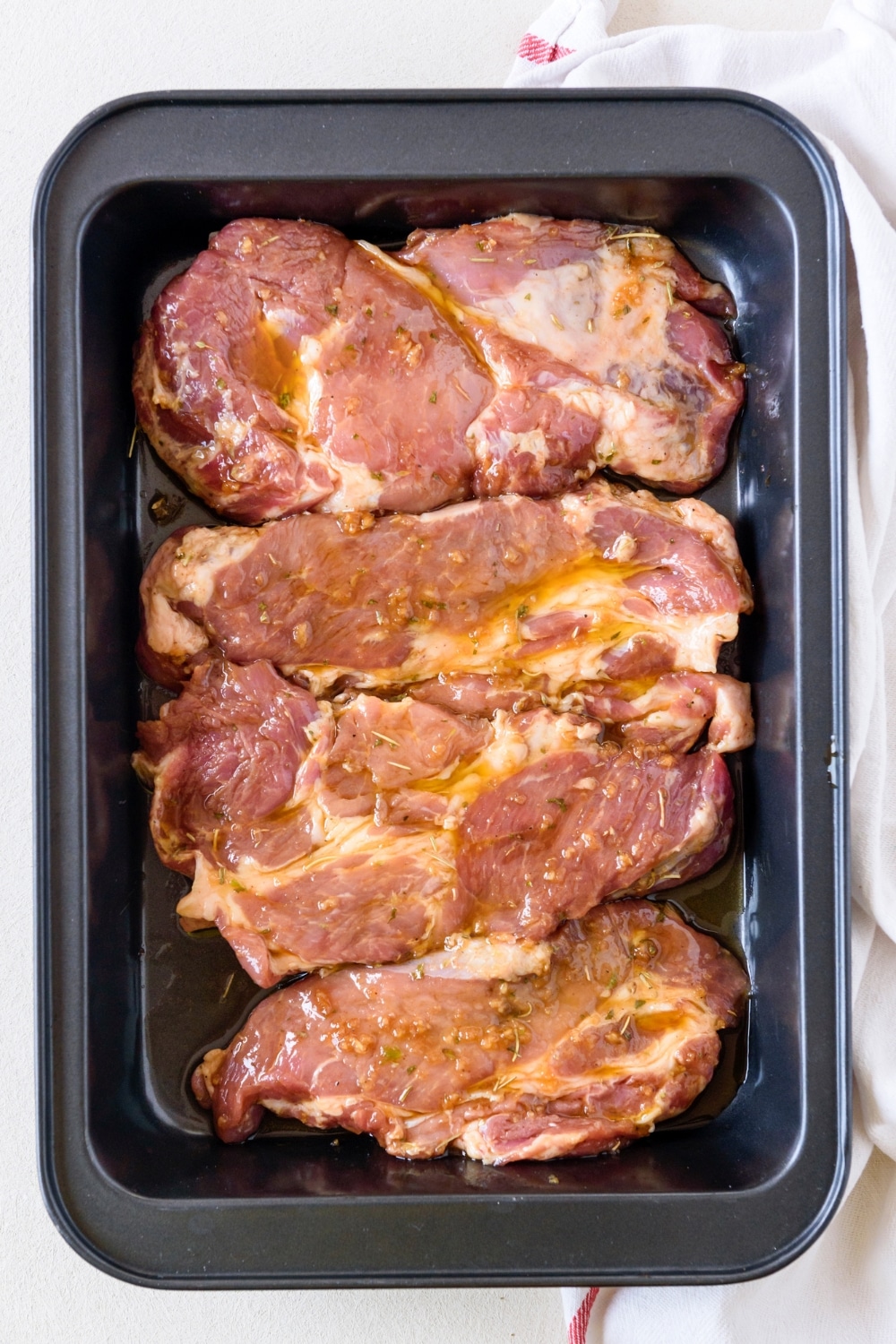 A baking dish filled with marinating pork chops.