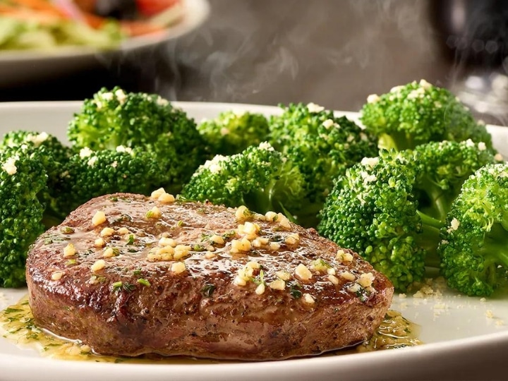A piece of steak with broccoli on a white plate.