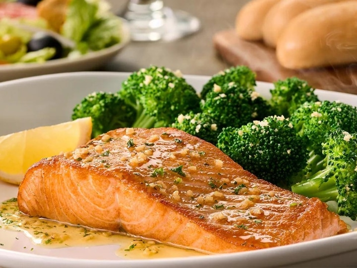 A piece of salmon with broccoli on a white plate.