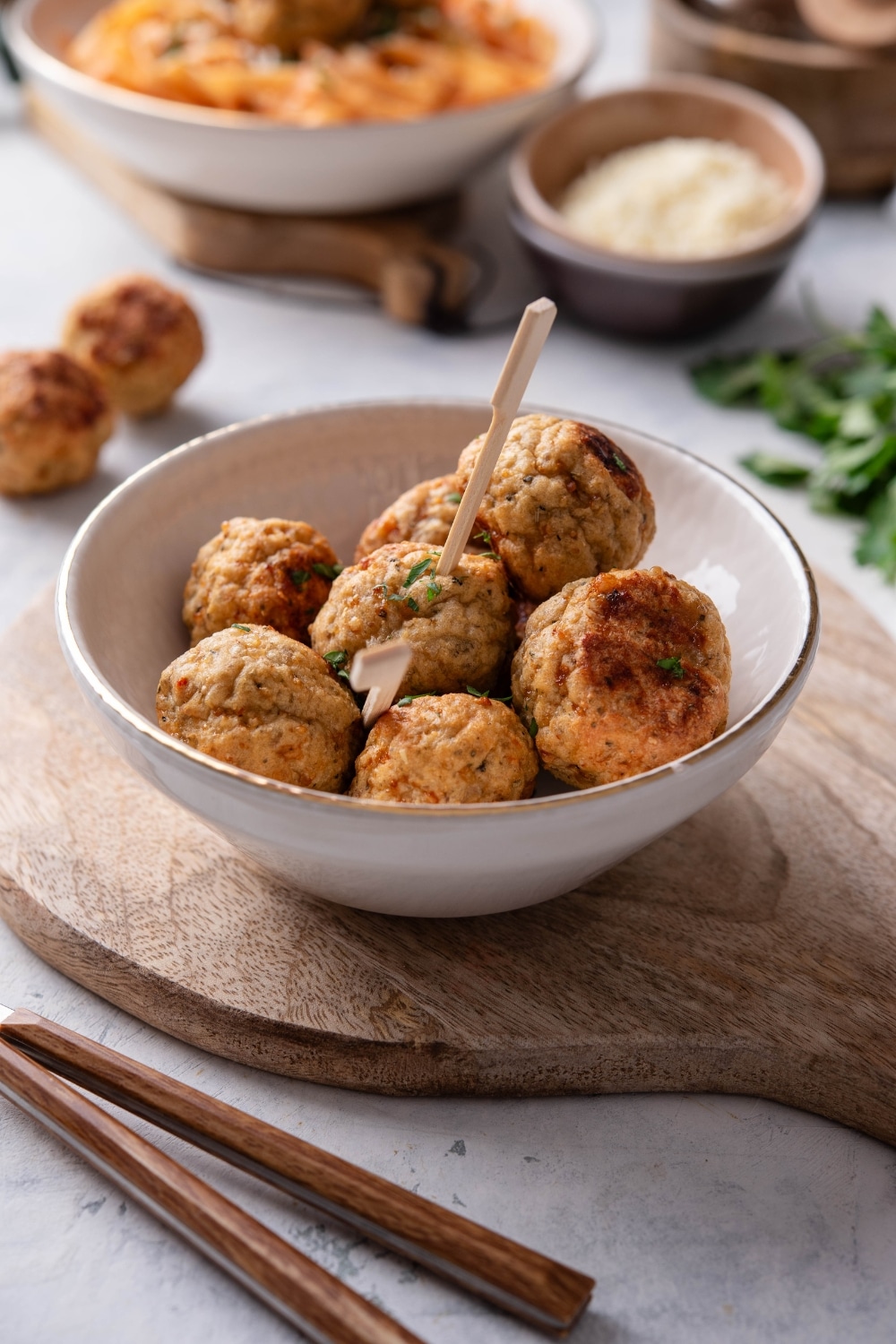 A bowl filled with meatballs with two toothpicks sticking out of two meatballs.