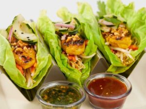 Three cheesecake factory Asian Chicken Lettuce Wrap Tacos in a metal taco holder.