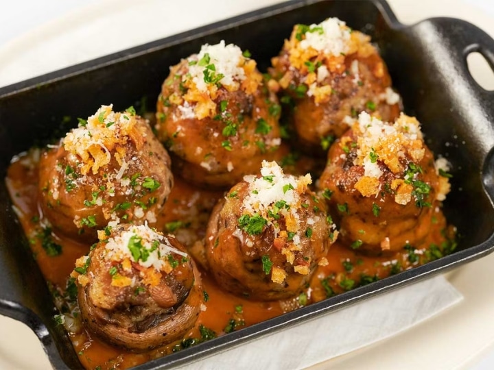 Six stuffed mushrooms in a black skillet.