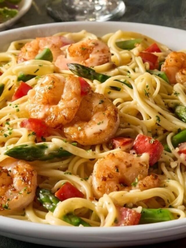 Shrimp, asparagus, and tomatoes with spaghetti and sauce in a bowl.