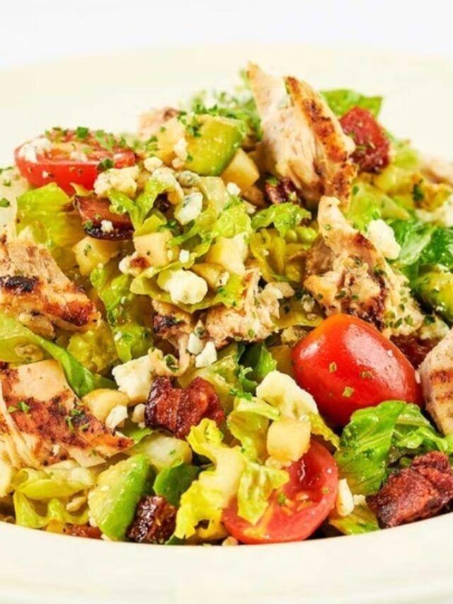 Grilled chicken and chopped salad greens with tomatoes in a white bowl .