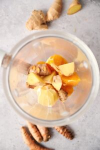 Ginger, oranges, lemons, and turmeric in a blender.