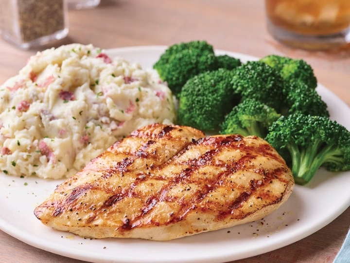 A grilled chicken breast on a plate with mashed potatoes and broccoli.