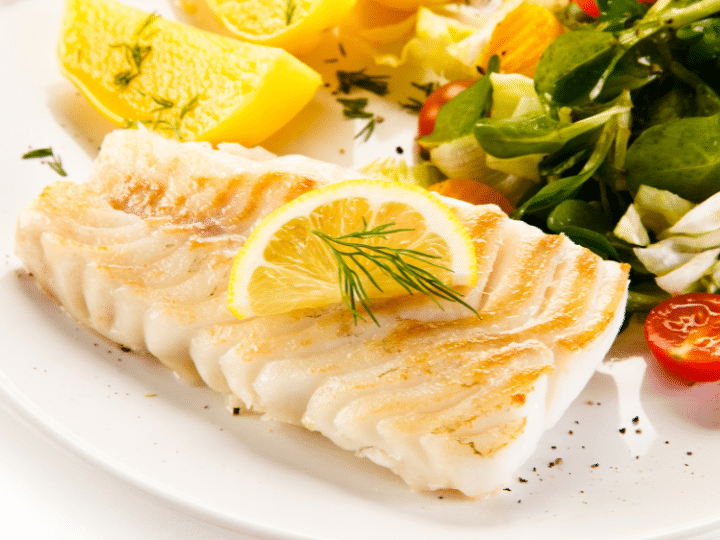 A piece of cooked cod on a plate.